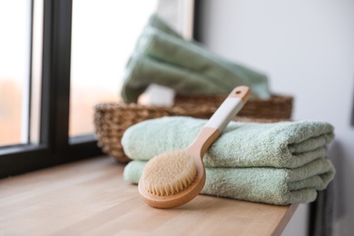 Photo of Clean soft towels and shower brush on windowsill in bathroom