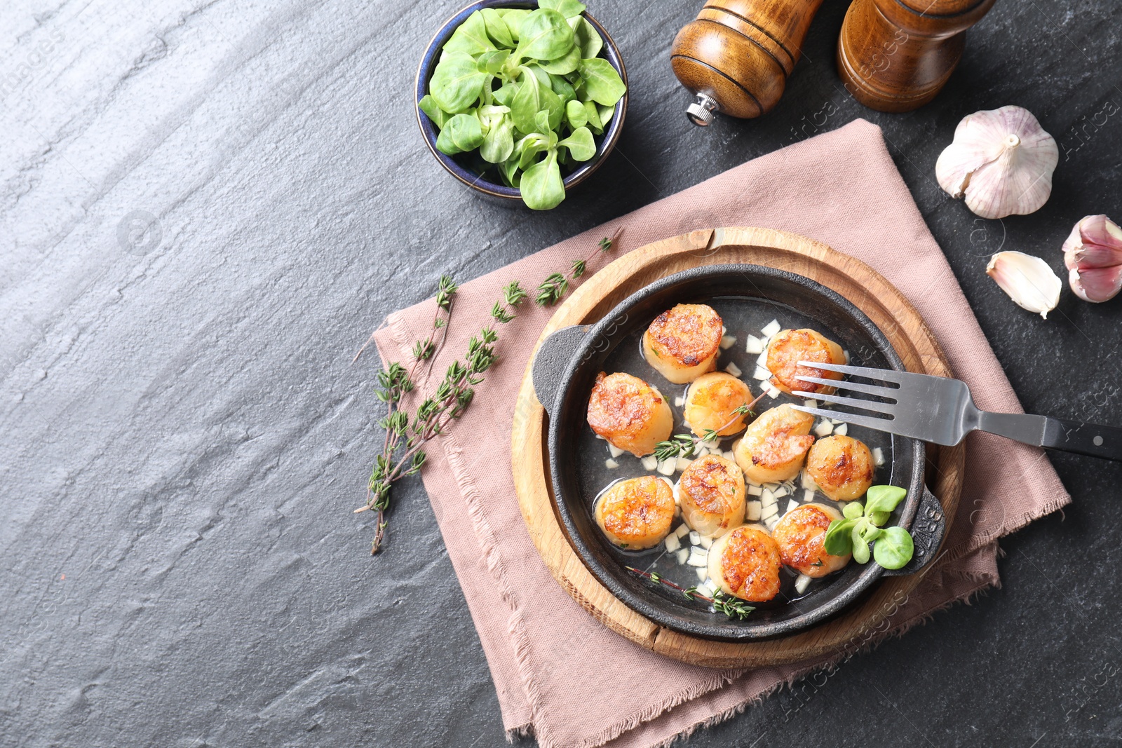 Photo of Delicious fried scallops in dish served on dark gray textured table, flat lay. Space for text