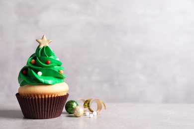 Photo of Christmas tree shaped cupcake and decor on light grey background. Space for text