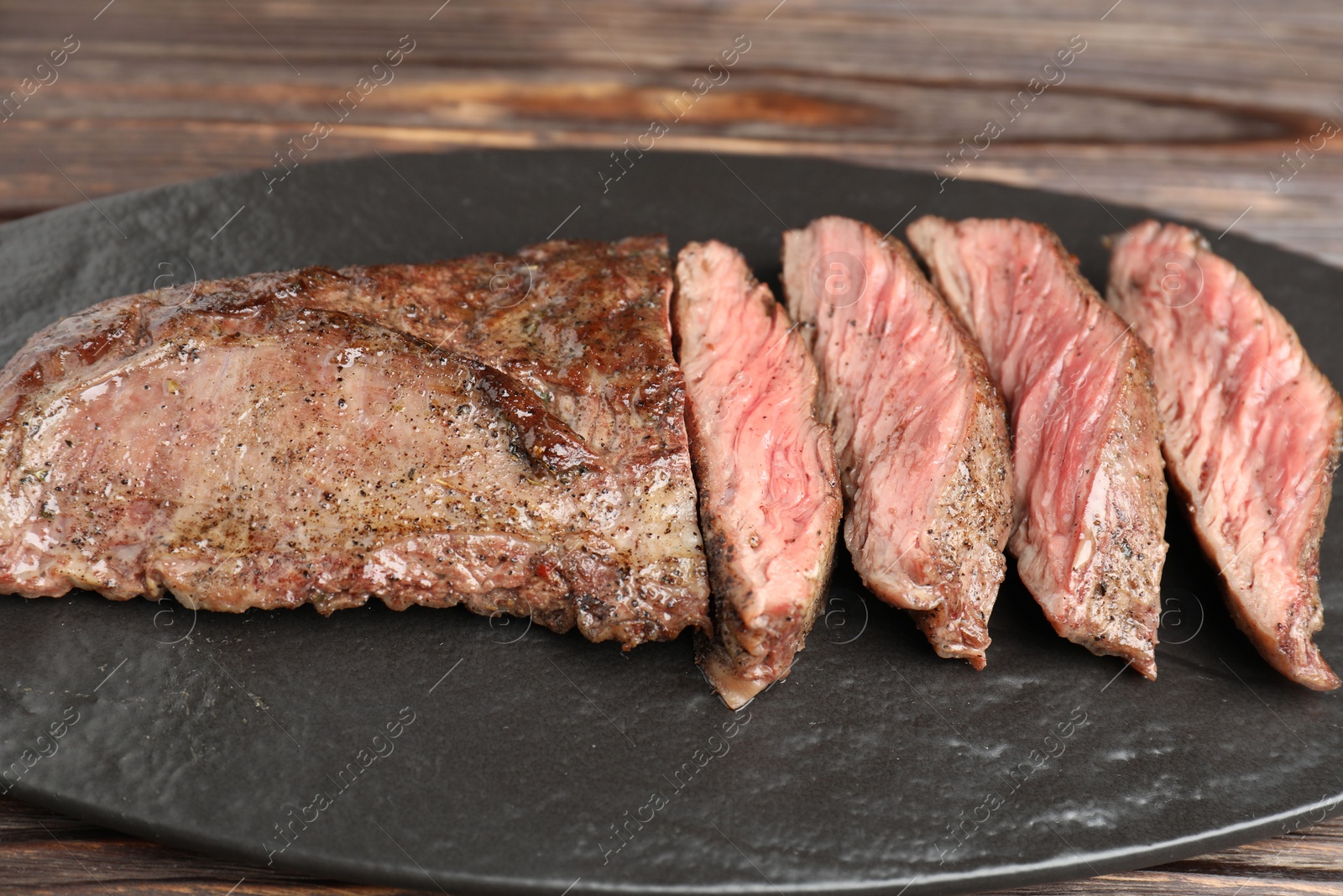 Photo of Pieces of delicious grilled beef meat on wooden table, closeup