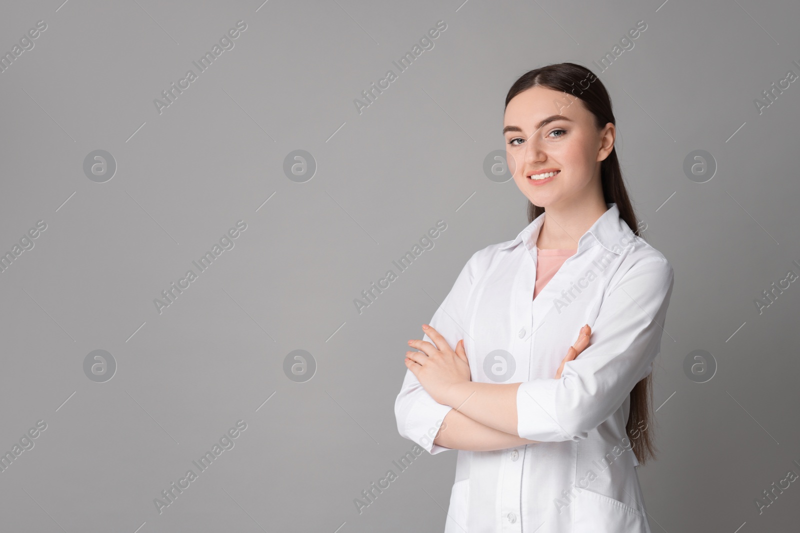 Photo of Cosmetologist in medical uniform on grey background, space for text