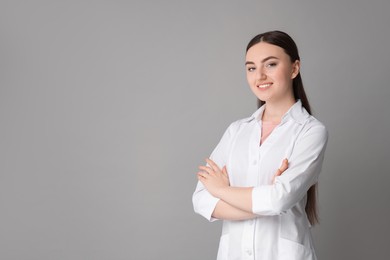 Photo of Cosmetologist in medical uniform on grey background, space for text