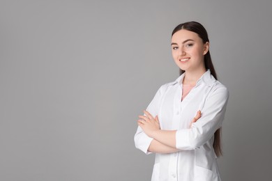 Cosmetologist in medical uniform on grey background, space for text