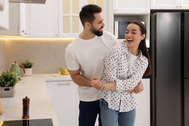 Photo of Happy lovely couple dancing together in kitchen