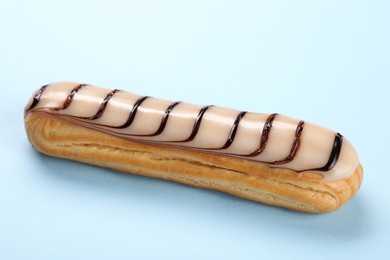 Delicious eclair covered with glaze on light blue background