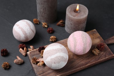 Photo of Bath bombs, dry flowers and burning candle on black table