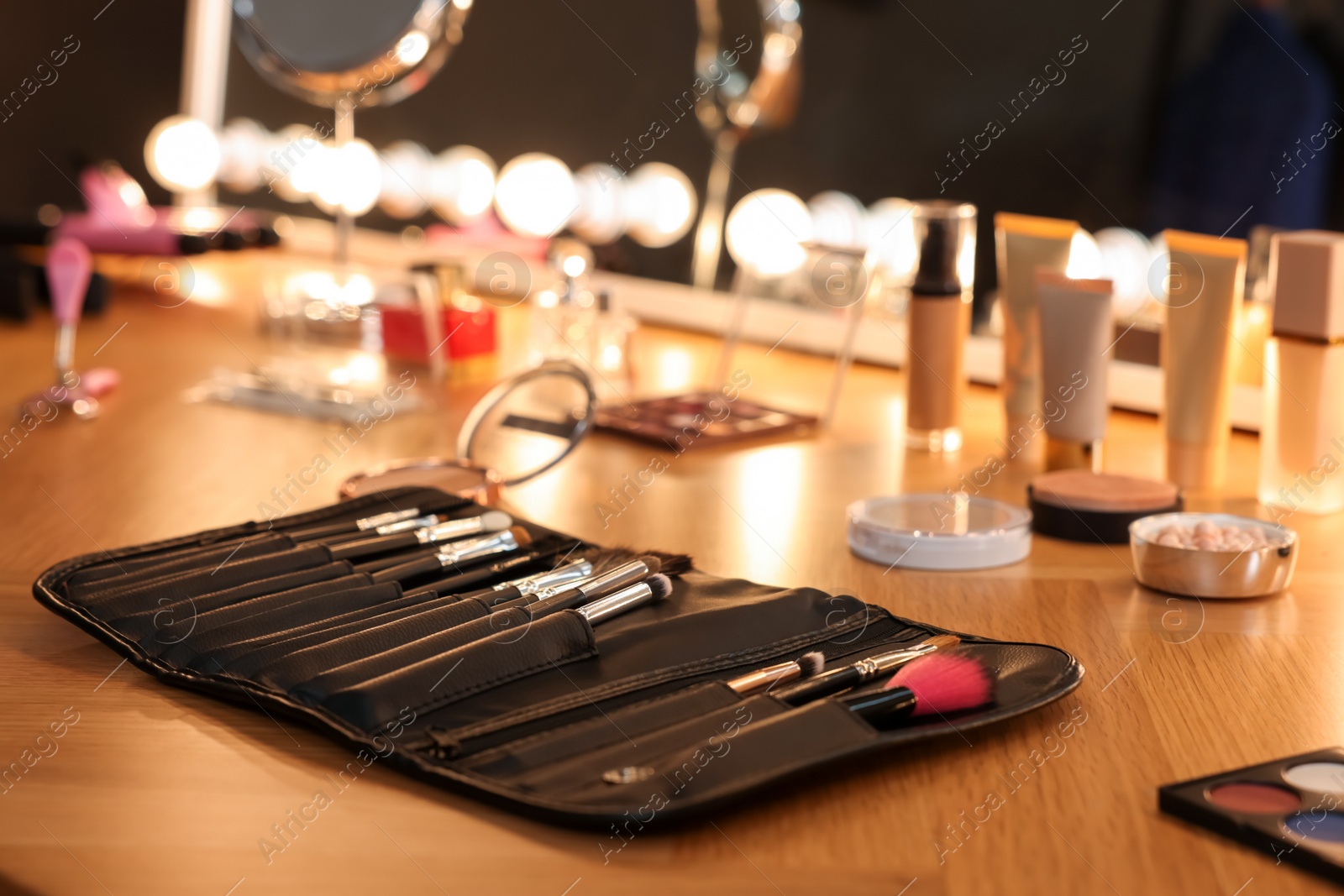 Photo of Set of makeup brushes and cosmetics on wooden table