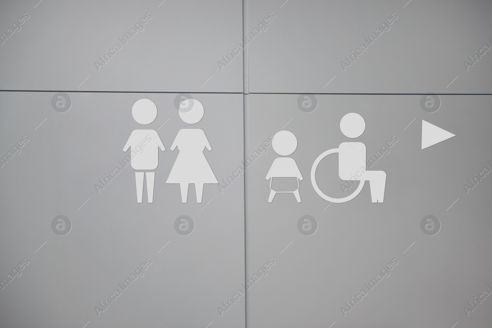 Image of White public toilet sign with arrow showing direction on wall