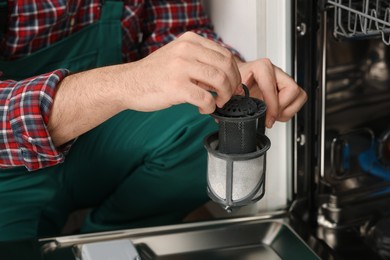 Repairman holding drain filter near dishwasher, closeup