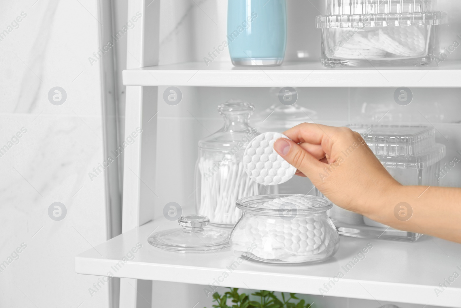 Photo of Young woman taking cotton pad from jar indoors, closeup