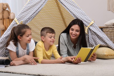 Photo of Mother with children reading book in wigwam at home