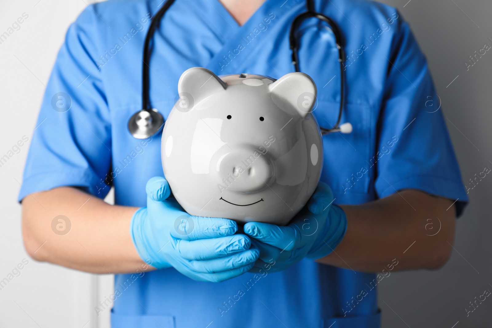 Photo of Doctor holding piggy bank on white background, closeup. Medical insurance