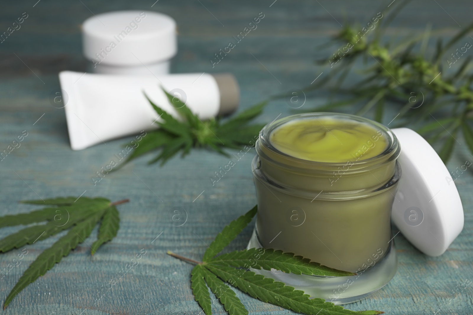 Photo of Jar of hemp cream on blue wooden table, space for text. Organic cosmetics