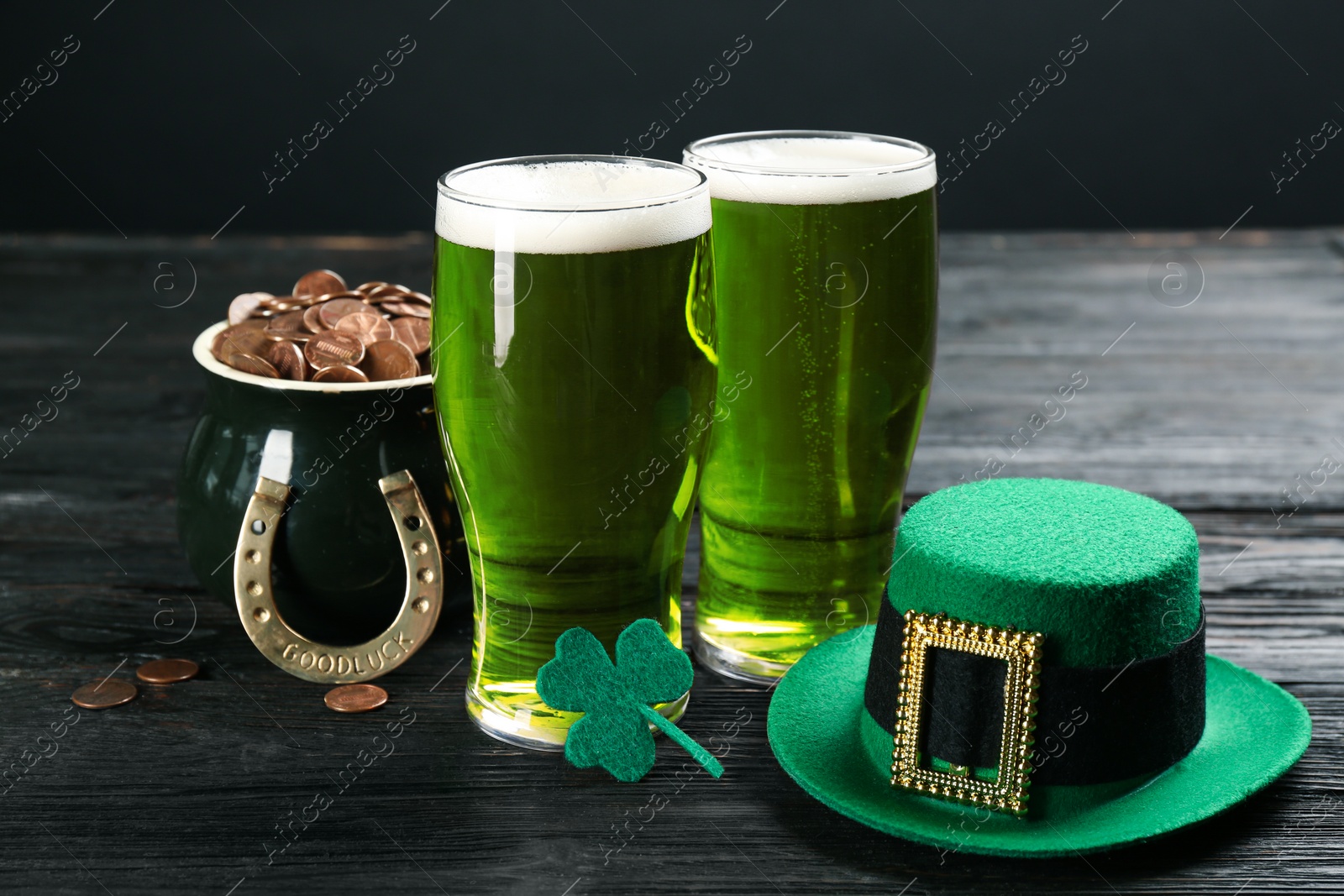 Photo of Composition with green beer and clover on black wooden table. St. Patrick's Day celebration