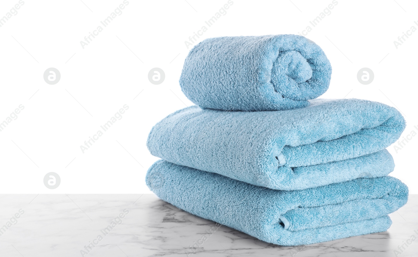 Photo of Fresh towels on marble table against white background. Space for text