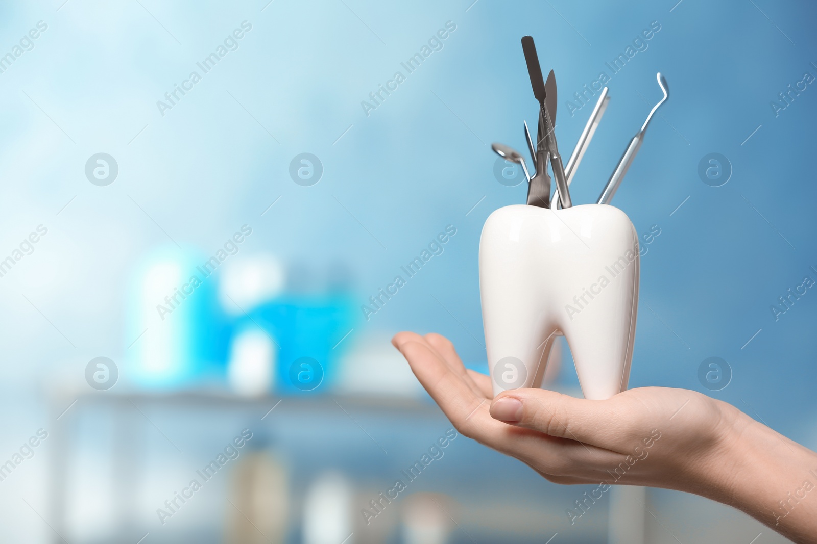 Photo of Dentist with tooth shaped holder full of professional tools in clinic, closeup. Space for text