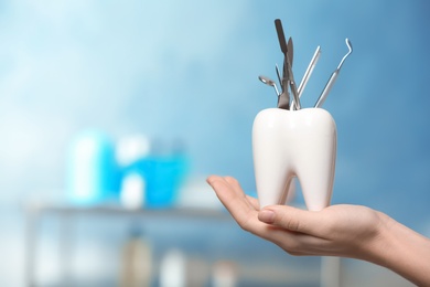 Photo of Dentist with tooth shaped holder full of professional tools in clinic, closeup. Space for text