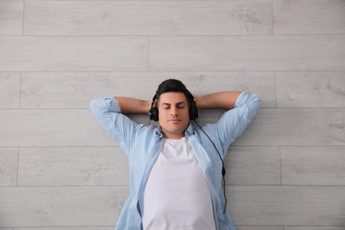 Man with headphones lying on warm floor, top view. Heating system