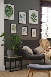 Photo of Beautiful artworks and comfortable sofa in stylish room. Interior design