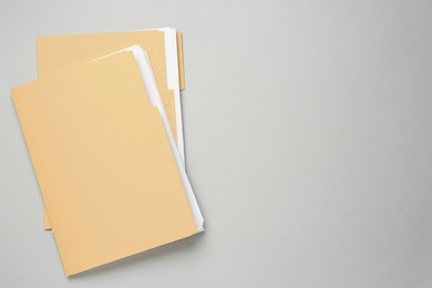 Photo of Yellow files with documents on light grey background, top view. Space for text