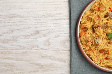 Delicious pilaf with meat on white wooden table, top view. Space for text