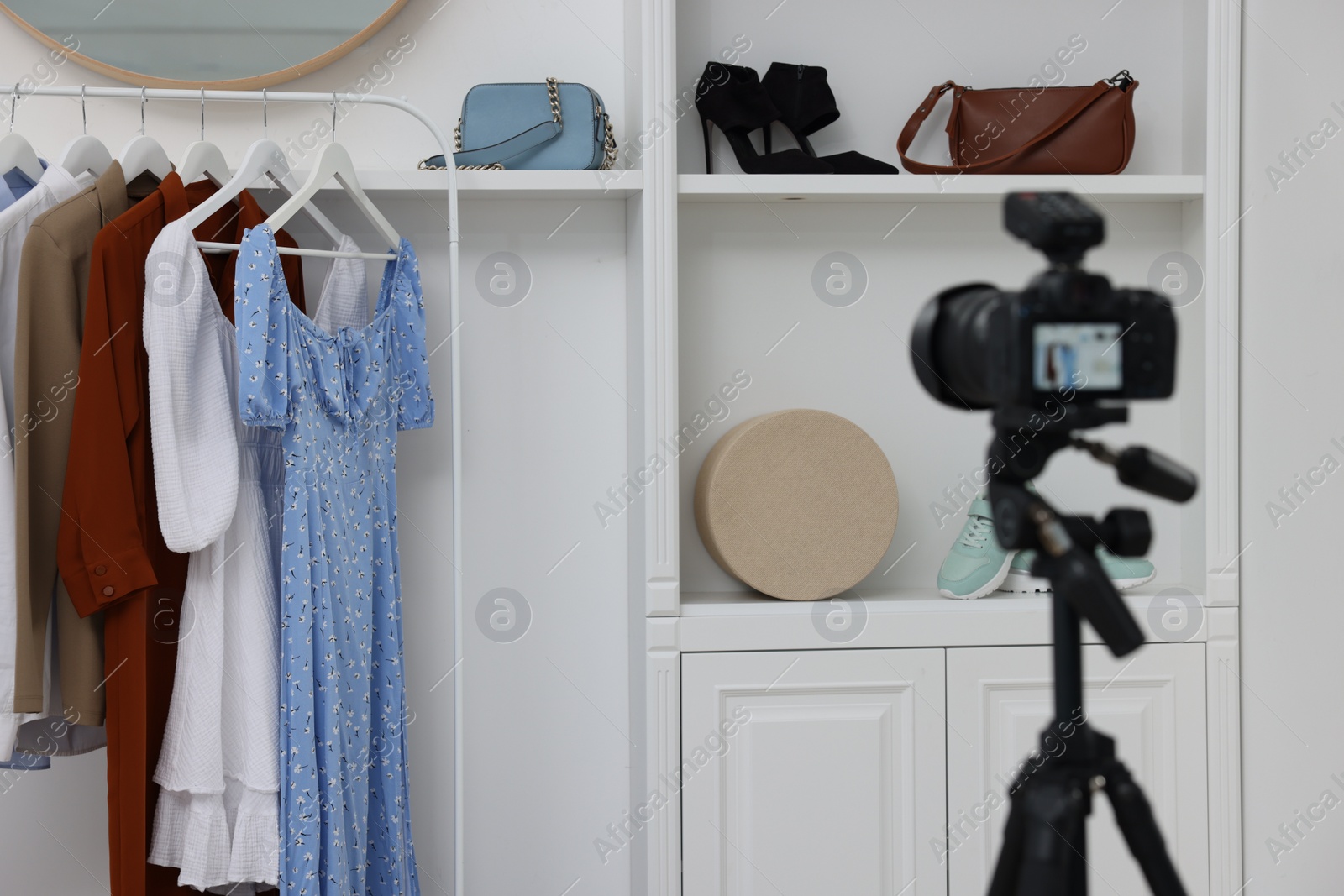 Photo of Fashion blogger's workplace. Shoes, clothes, camera and stylish furniture indoors