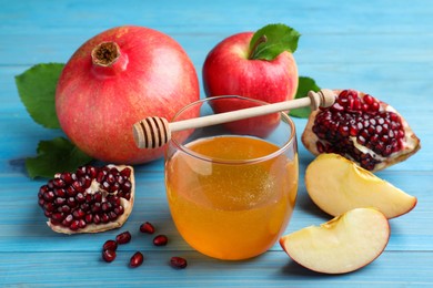 Photo of Honey, pomegranate and apples on light blue wooden table, closeup. Rosh Hashana holiday