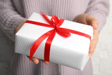 Young woman holding Christmas gift, closeup view