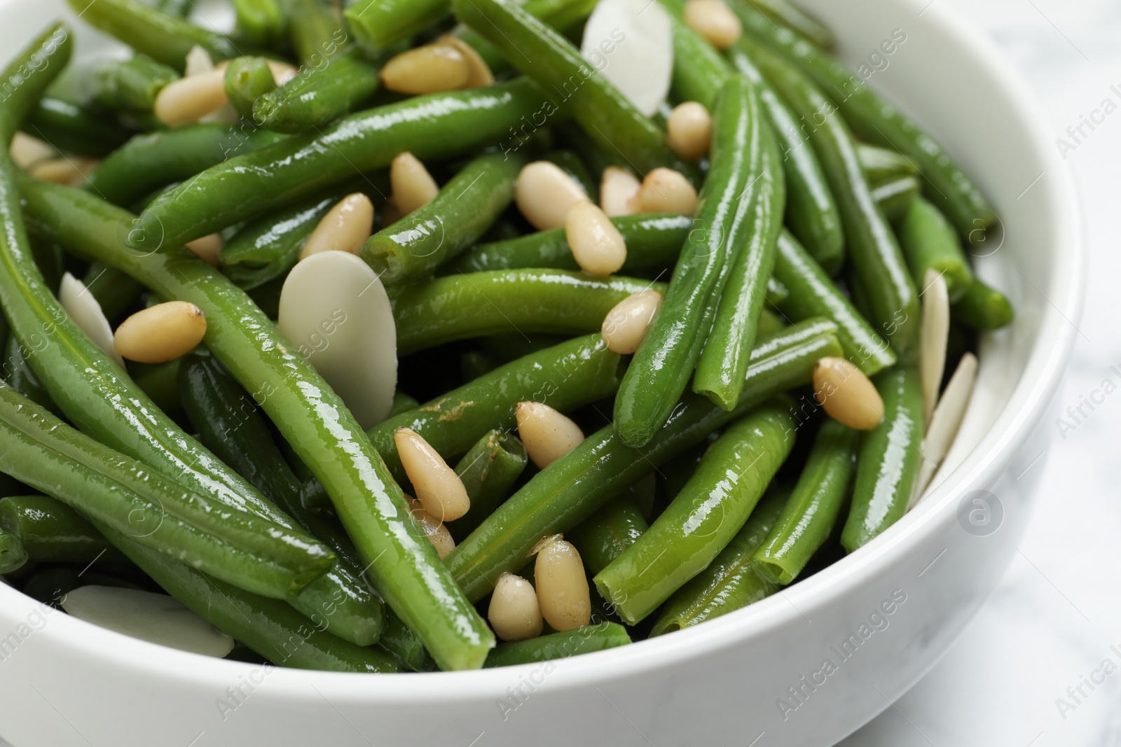 Photo of Bowl of tasty salad with green beans on white table, closeup