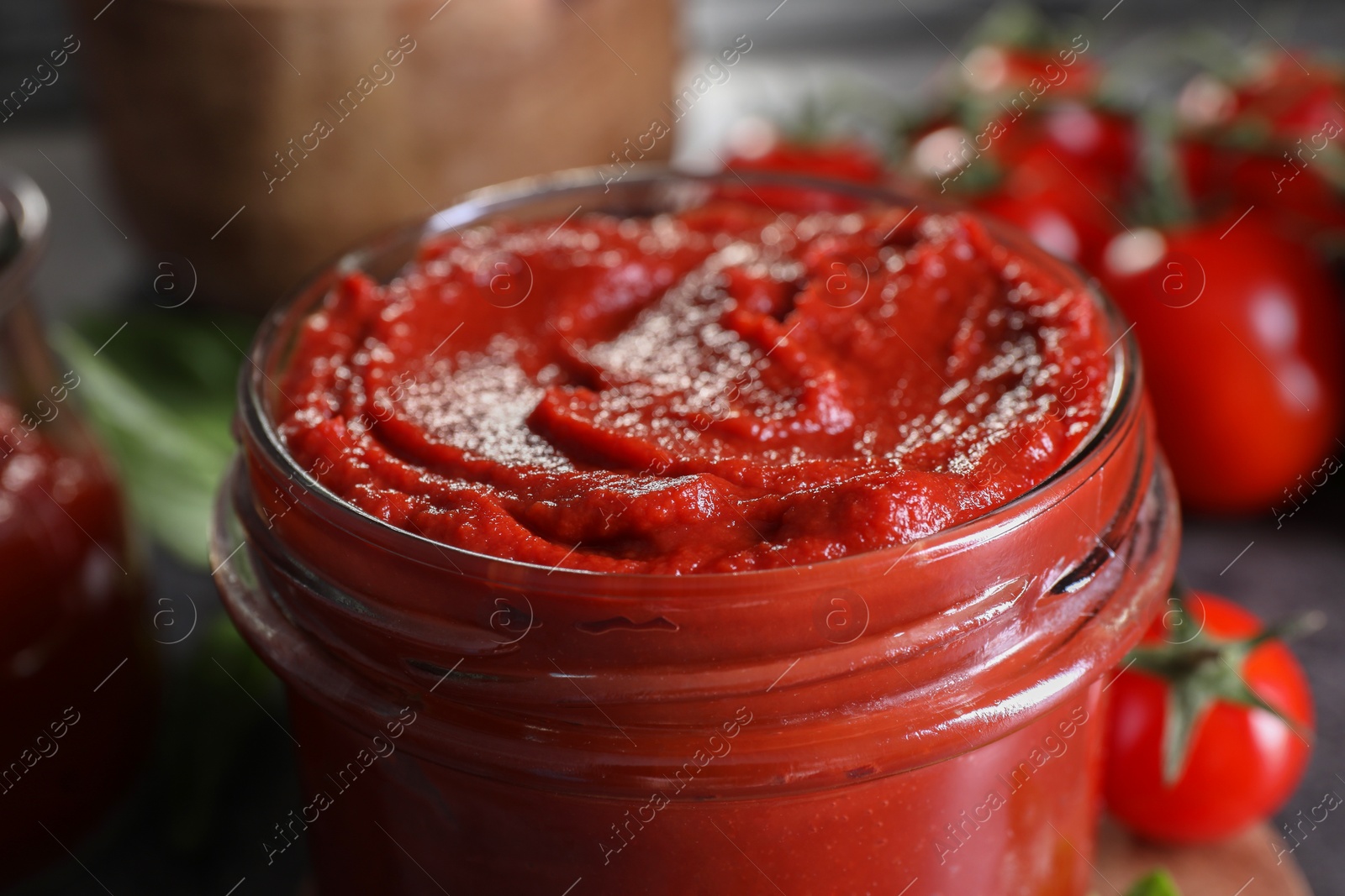 Photo of Jar of tasty tomato paste on table, closeup