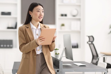 Portrait of smiling businesswoman with tablet in office. Space for text