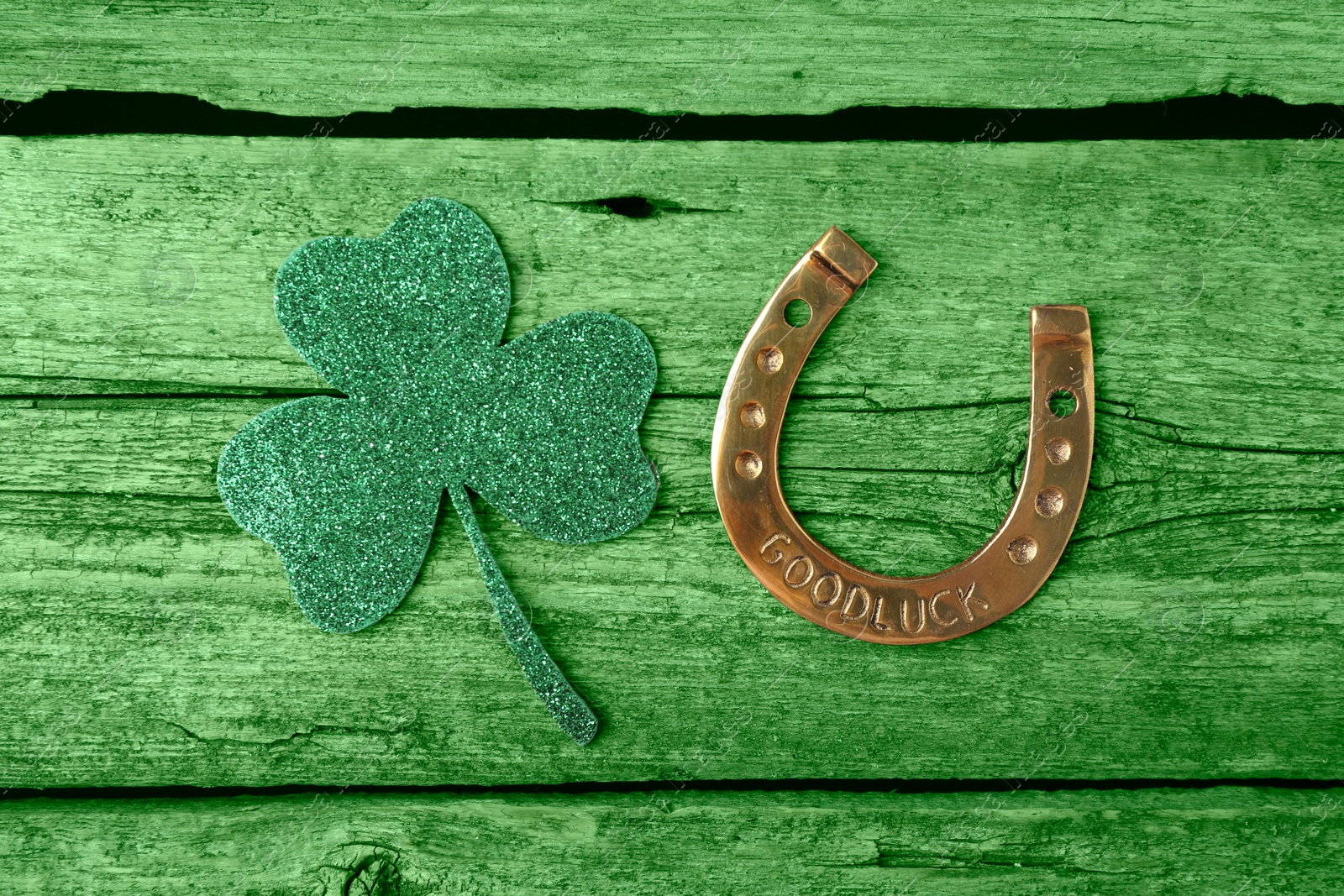 Image of St. Patrick's day. Decorative clover leaf and golden horseshoe on green wooden background, flat lay