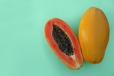 Photo of Fresh ripe papaya fruits on light turquoise background, flat lay. Space for text