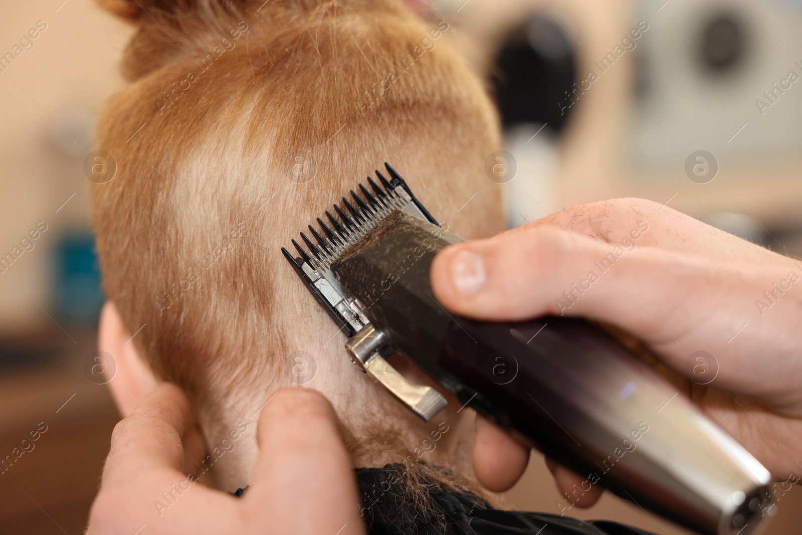 Photo of Professional hairdresser cutting boy's hair in beauty salon, closeup