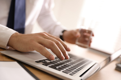 Man working with laptop in office, closeup of hand