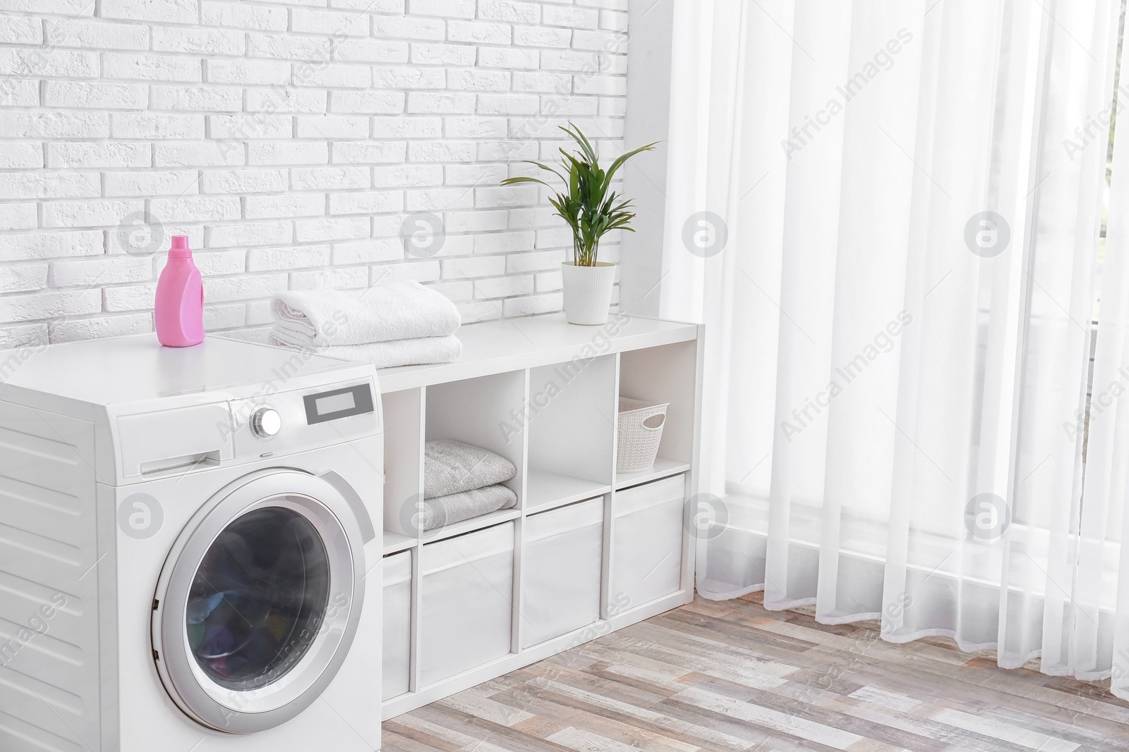 Photo of Modern washing machine near brick wall in laundry room interior, space for text