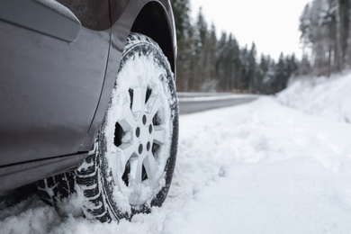 Closeup view of car in snow near road. Space for text