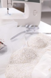 Beautiful wedding dress with embroidered bustline on table in dressmaking workshop