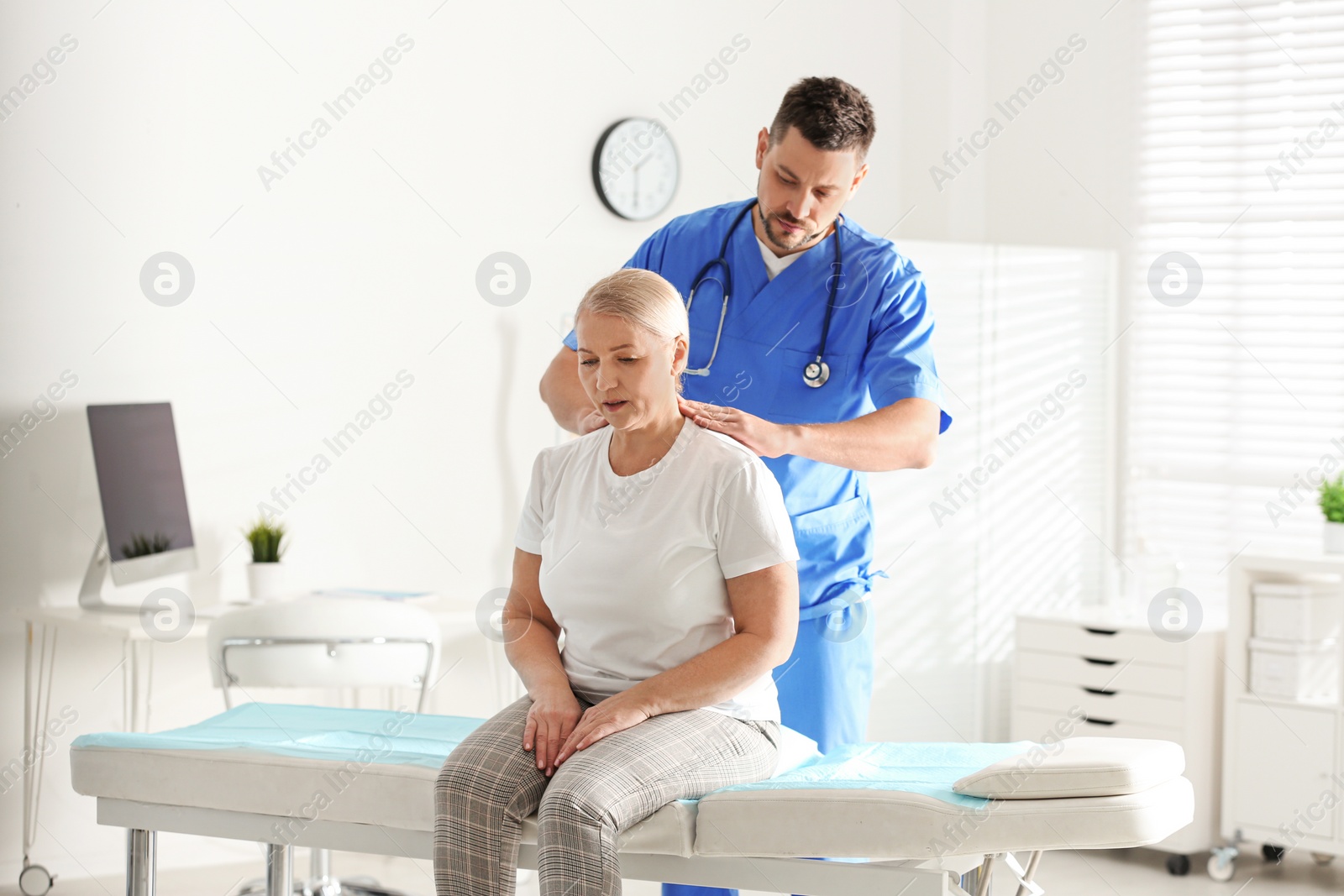 Photo of Male orthopedist examining patient with injured neck in clinic