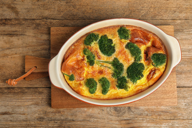 Tasty broccoli casserole in baking dish on wooden table, top view