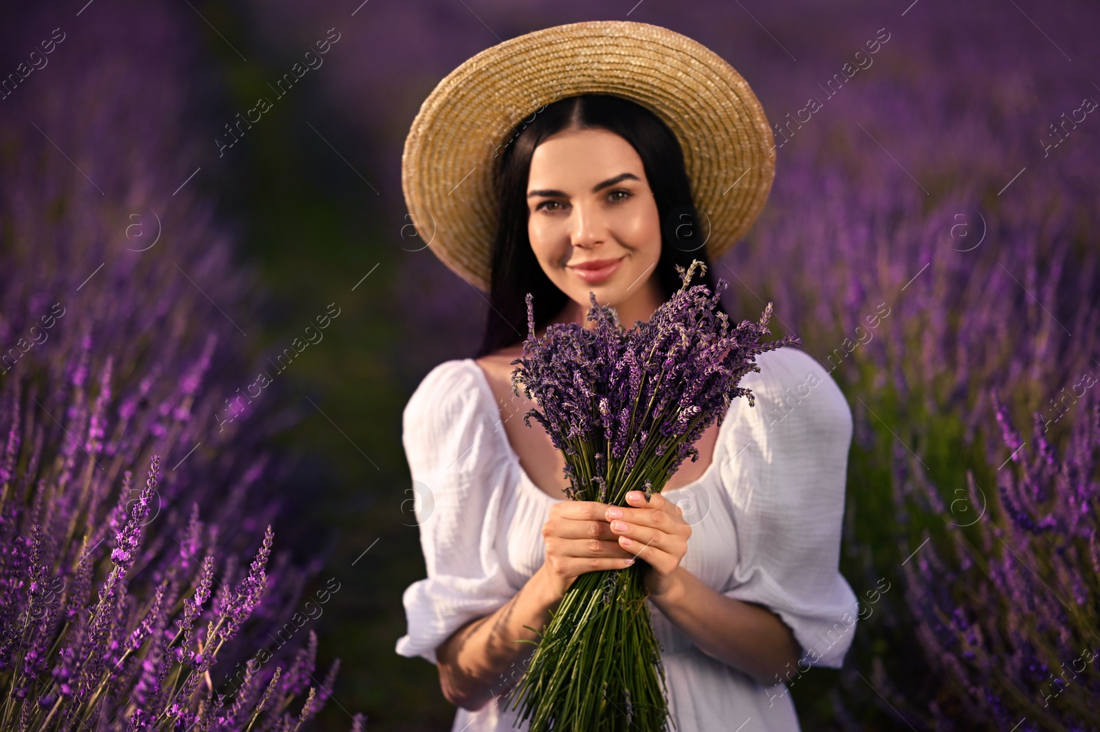 Photo of Beautiful young woman with bouquet in lavender field