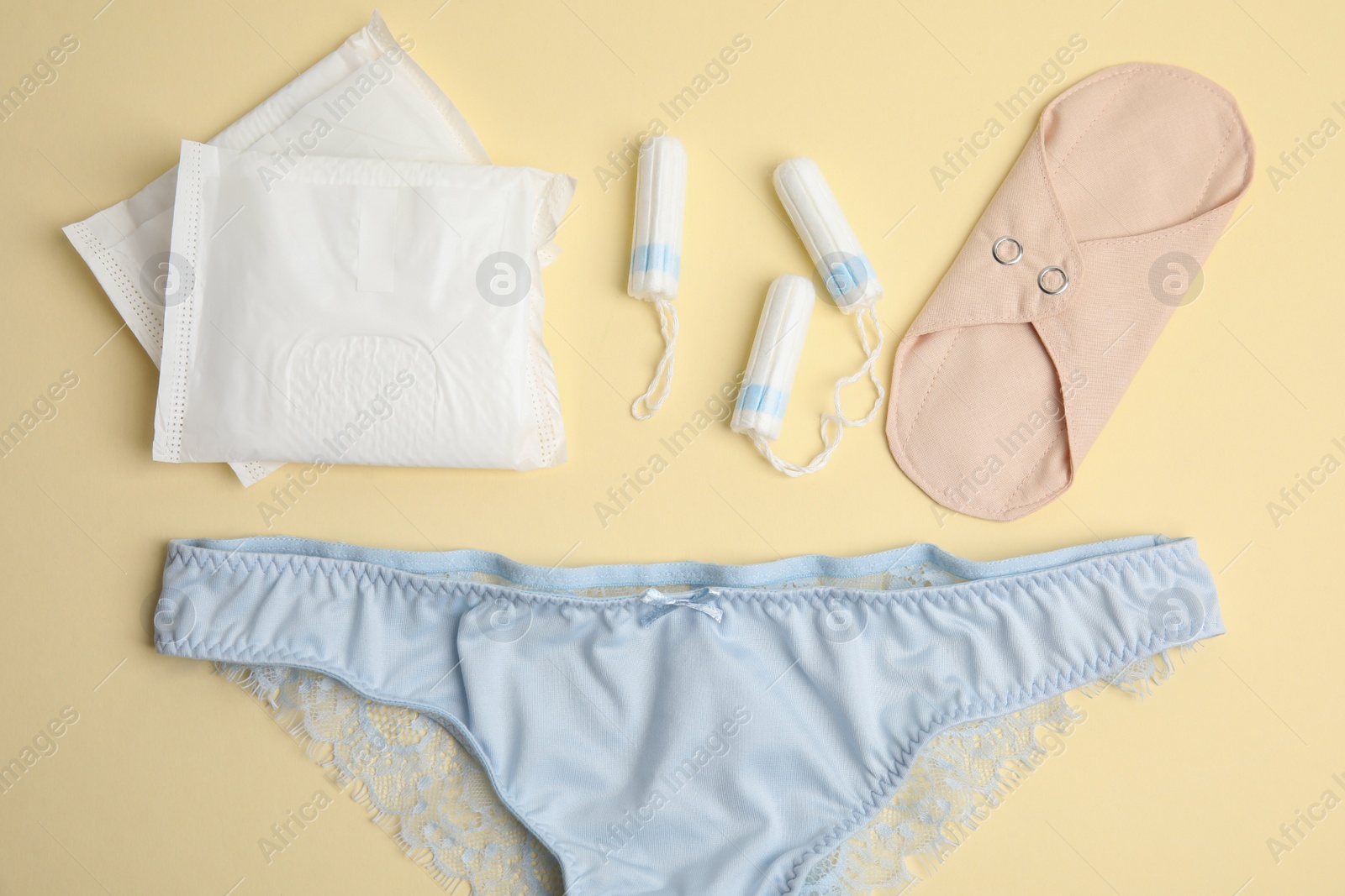 Photo of Tampons and other menstrual hygienic products on yellow background, flat lay