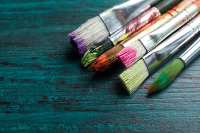 Different paint brushes on wooden table, closeup. Space for text