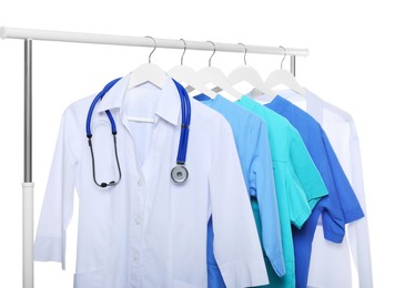 Photo of Doctor's gown with stethoscope and different medical uniforms on rack against white background