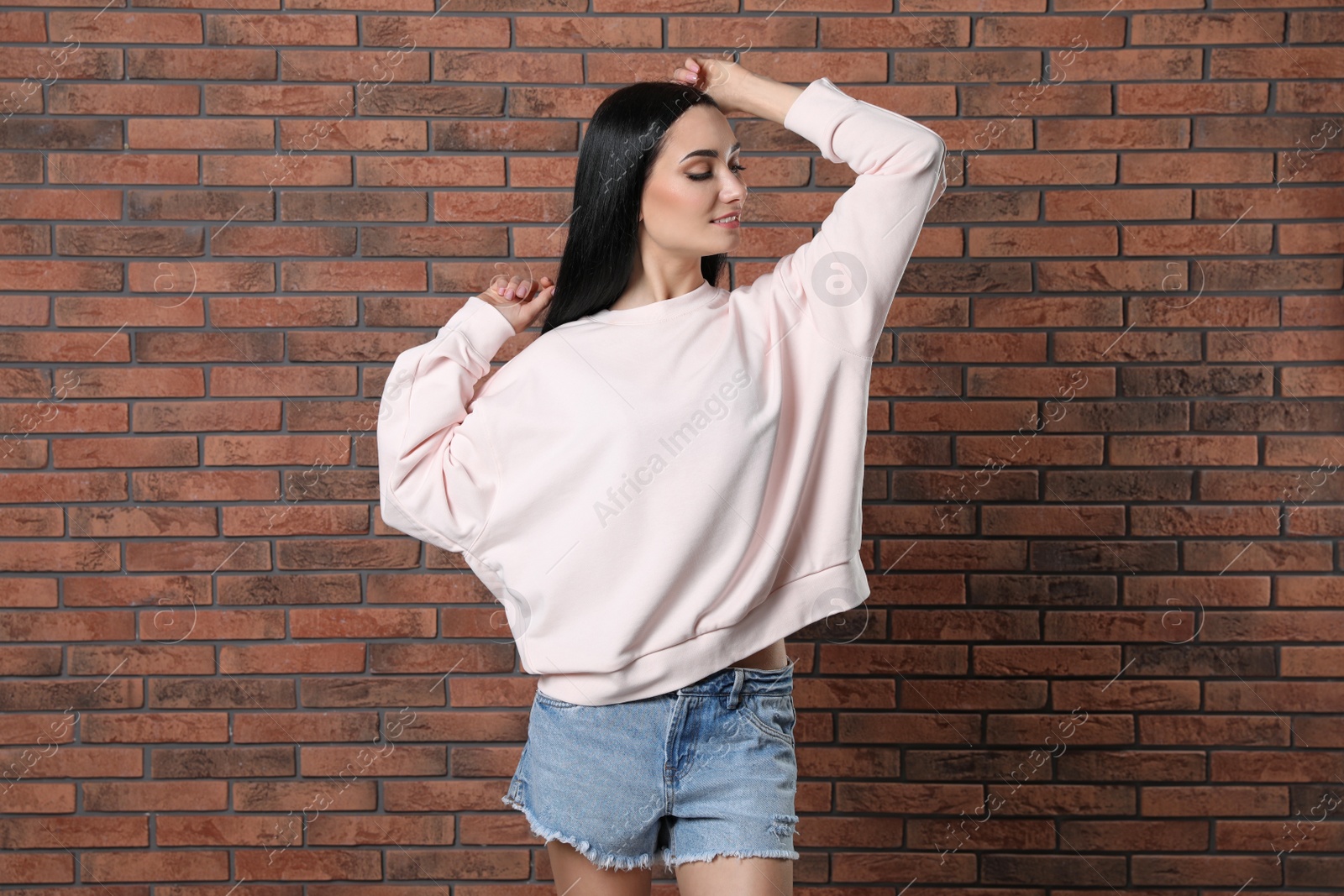 Photo of Portrait of young woman in sweater at brick wall. Mock up for design