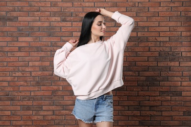 Photo of Portrait of young woman in sweater at brick wall. Mock up for design
