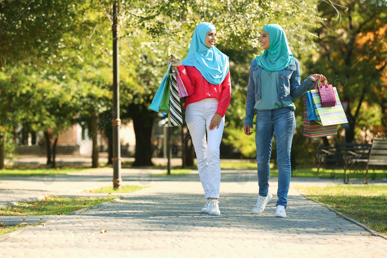 Photo of Muslim women with shopping bags walking in park