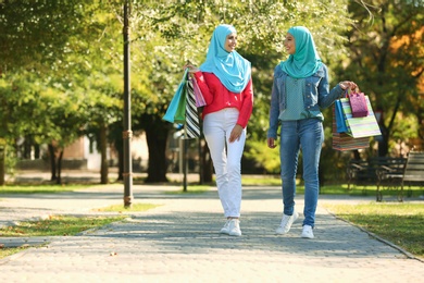 Photo of Muslim women with shopping bags walking in park