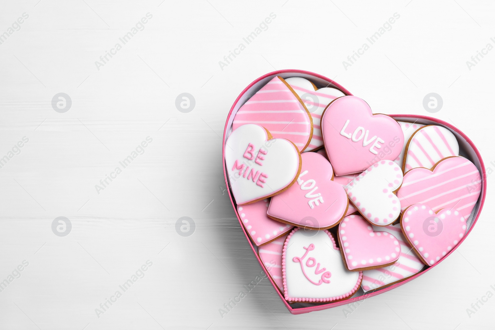 Photo of Delicious heart shaped cookies in box on white wooden table, top view with space for text. Valentine's Day