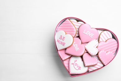 Delicious heart shaped cookies in box on white wooden table, top view with space for text. Valentine's Day